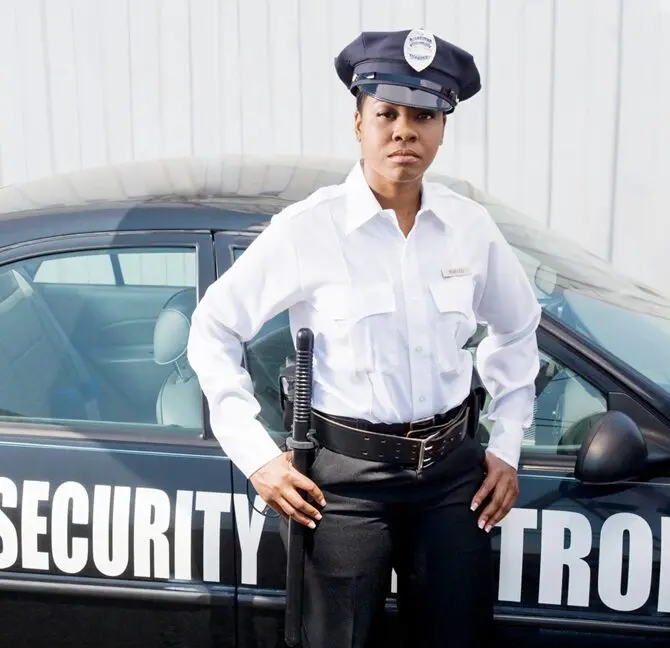 A security guard standing in front of a car.